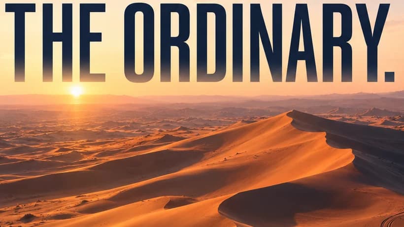 Close-up of the condensed navy words The ordinary fading into a hazy sunrise above orange dunes