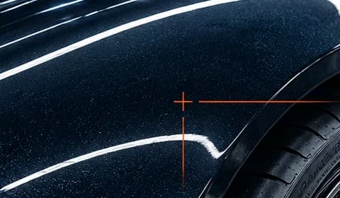 Close-up of midnight blue paint with metallic flake, an orange crosshair and the wheel arch over the tyre