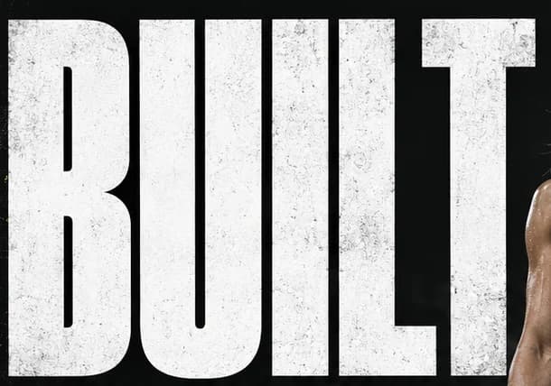 Close-up of the word BUILT in tall compressed white capitals with a worn, chalky texture on black.