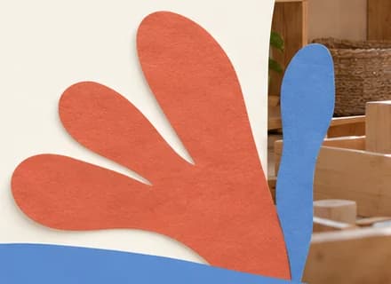 Coral paper cut-out shaped like a palm frond beside a blue paper splash and the top of a blue wave.