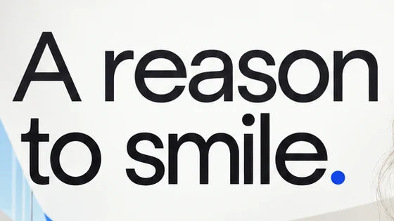 Close-up of the headline A reason to smile. in a black geometric sans, ending in a cobalt full stop.