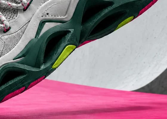 Close-up of the sneaker's dark green sculpted sole with a lime pod and pink edging, floating over pink